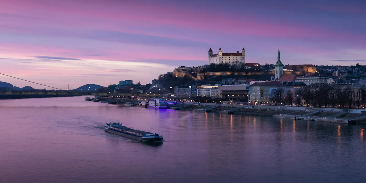 A picturesque view of Bratislava Castle and Danube River at sunset, showcasing Slovakia's scenic cityscape.