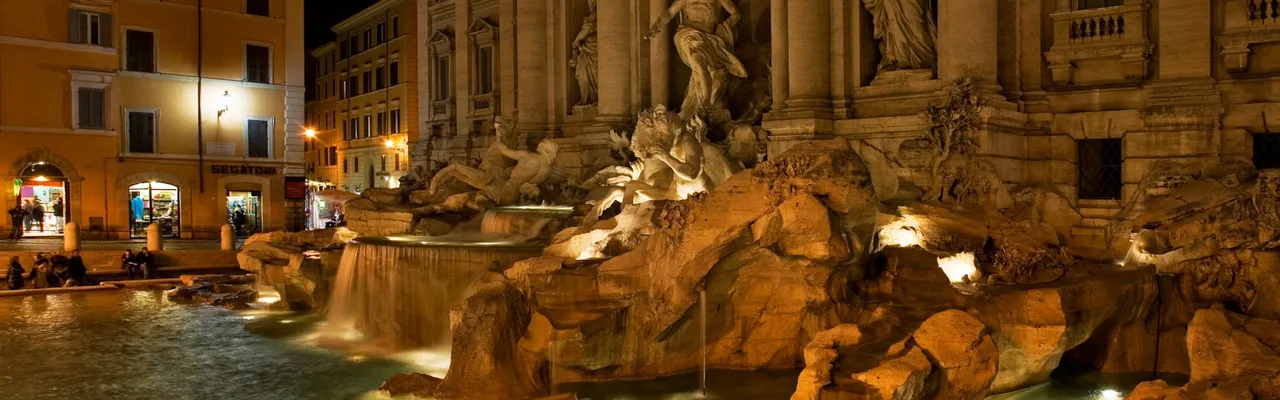 The iconic Trevi Fountain illuminated at night, showcasing its stunning Baroque architecture.