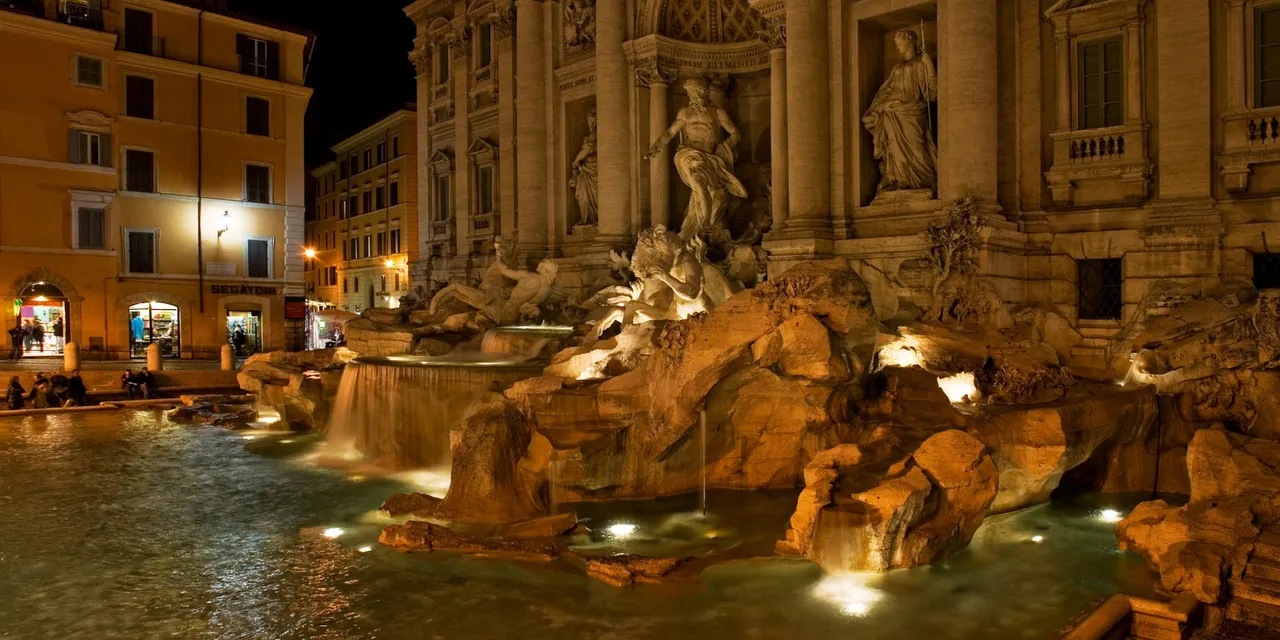 The iconic Trevi Fountain illuminated at night, showcasing its stunning Baroque architecture.