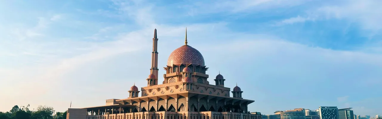 Scenic view of the majestic Putra Mosque in Putrajaya against a clear blue sky.