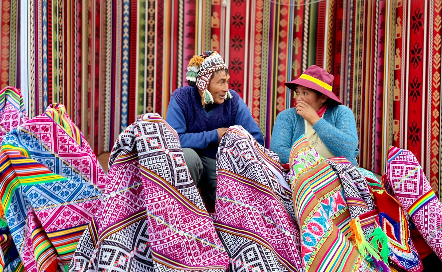 Vibrant Peruvian market showcasing traditional textiles with vendors engaging in conversation.