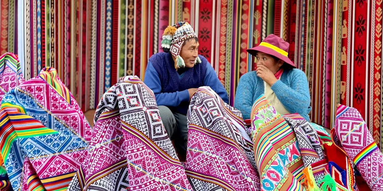 Vibrant Peruvian market showcasing traditional textiles with vendors engaging in conversation.