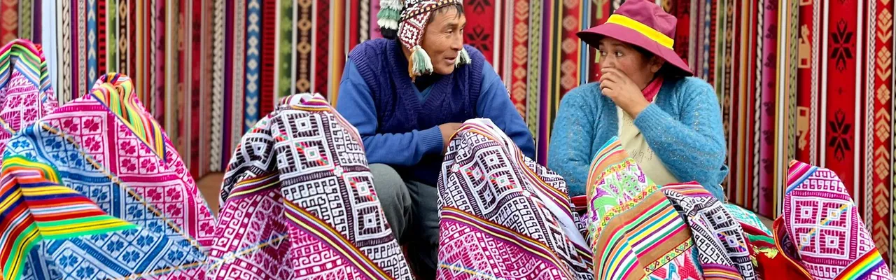 Vibrant Peruvian market showcasing traditional textiles with vendors engaging in conversation.