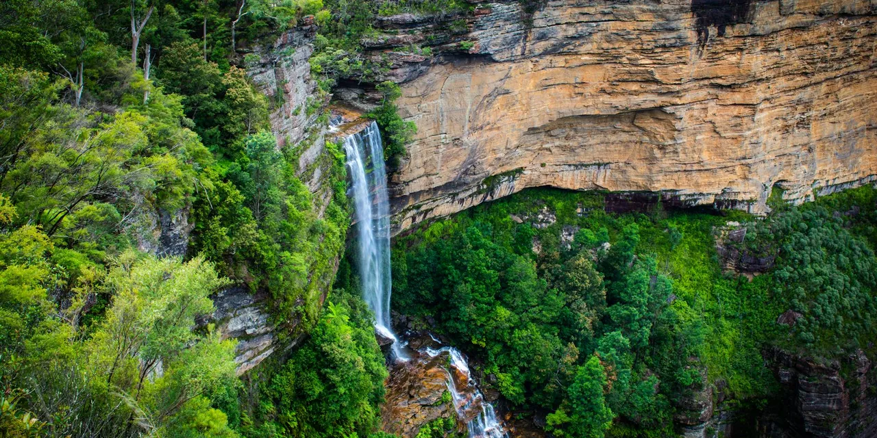 Spectacular waterfall cascading over sandstone cliffs in the lush Blue Mountains, Australia.