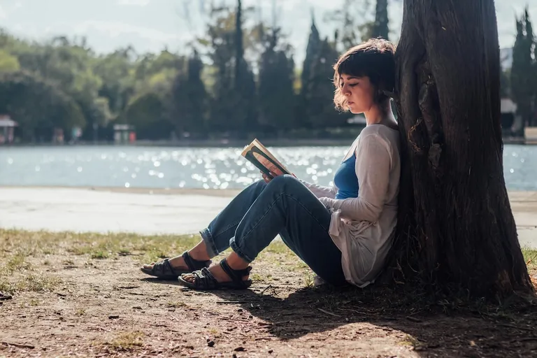 Woman with lupus reading in the shade in a park in Portugal