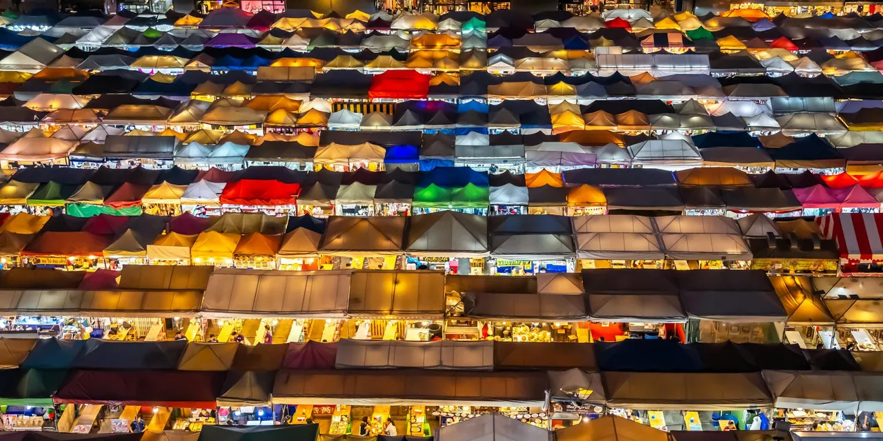 Aerial view of a colorful night market in Bangkok, Thailand. Vibrant stalls create a lively atmosphere.