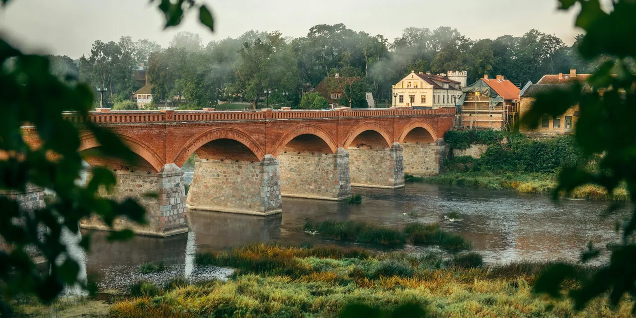 Historic brick arch bridge over a river at dawn, Latvia