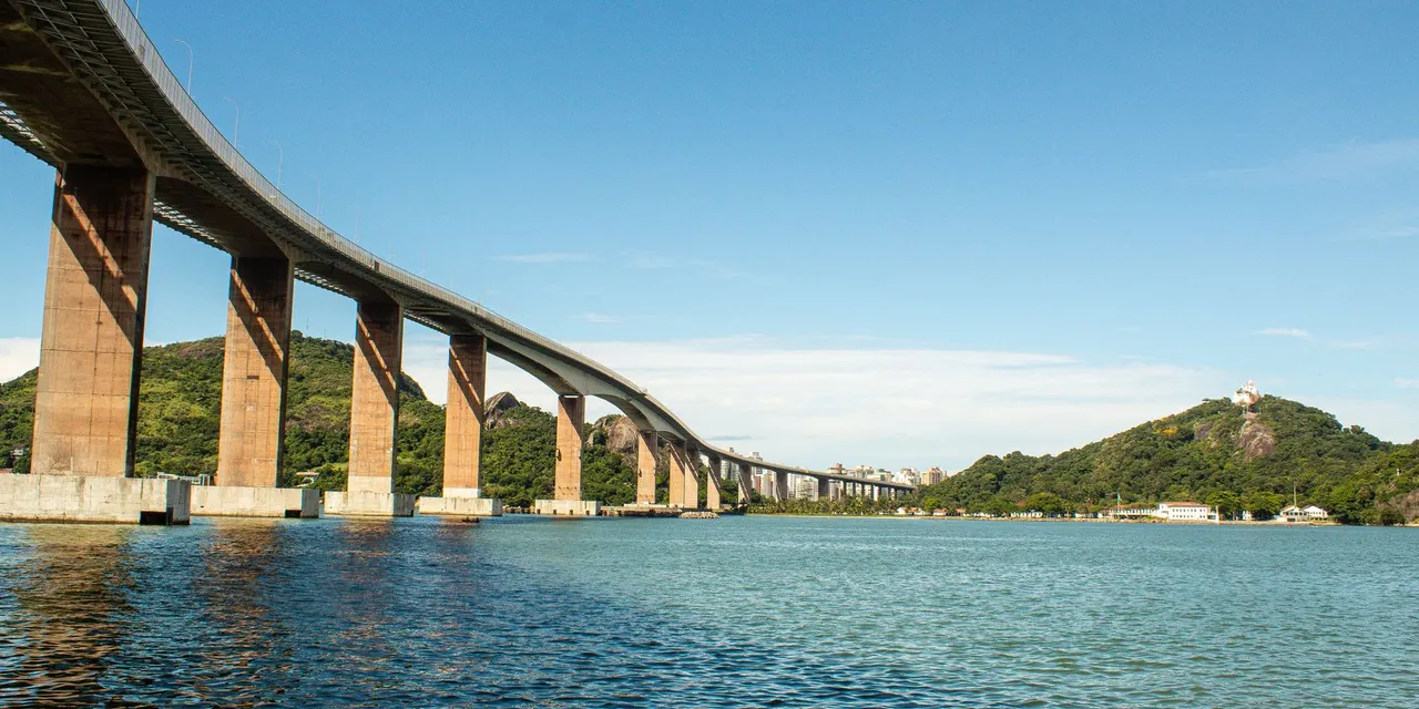 A stunning view of the Third Bridge in Vitória, Brazil against a clear blue sky and ocean.
