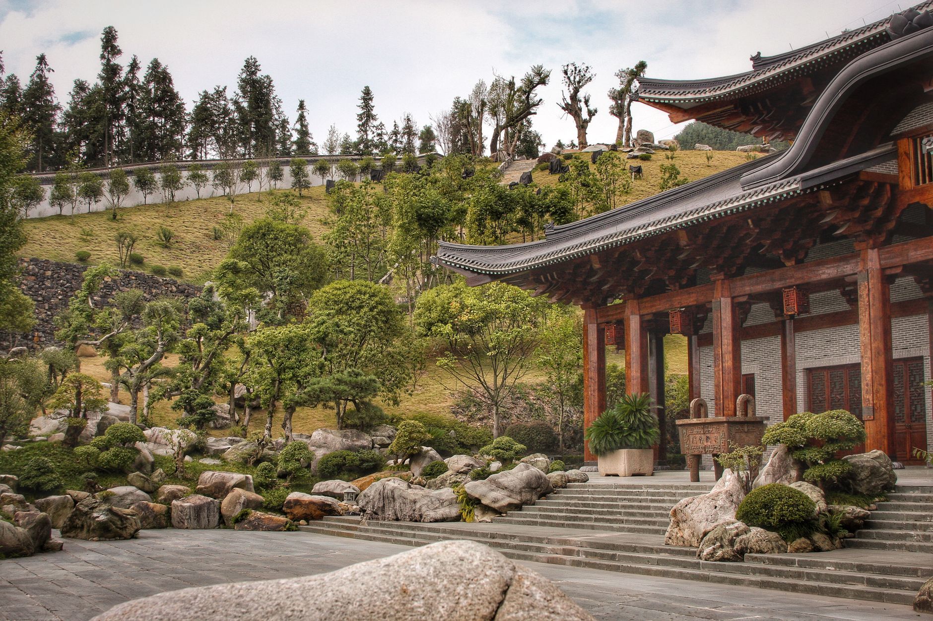 Tranquil view of a traditional Chinese temple surrounded by lush garden and rocks.