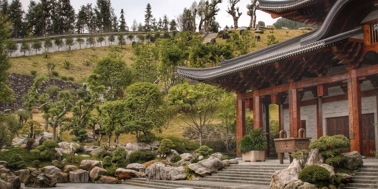 Tranquil view of a traditional Chinese temple surrounded by lush garden and rocks.