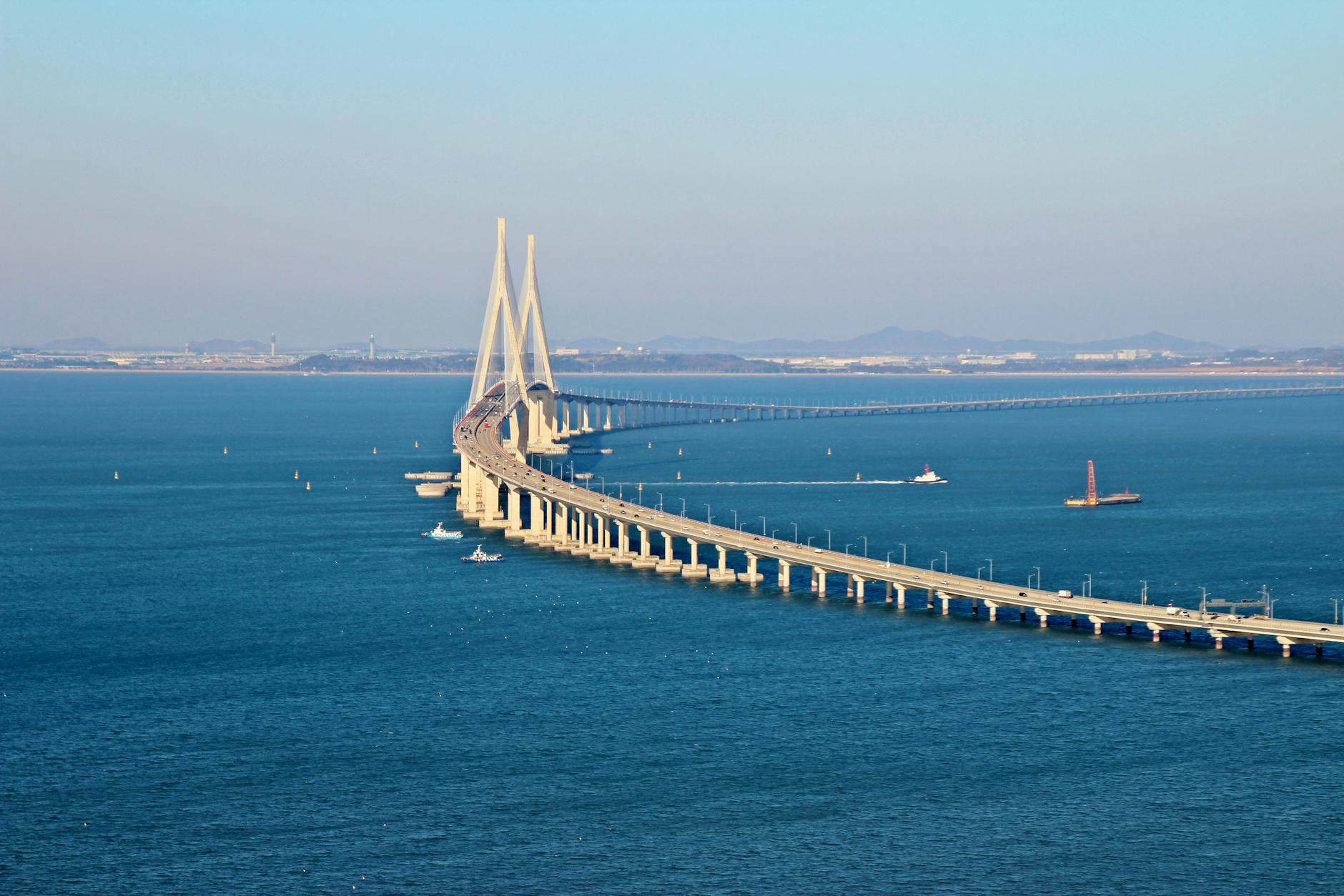 Stunning aerial view of Incheon Bridge spanning across blue ocean waters under a clear sky.