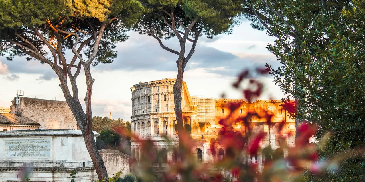 Beautiful view of the Colosseum framed by trees and flowers in Rome, Italy.