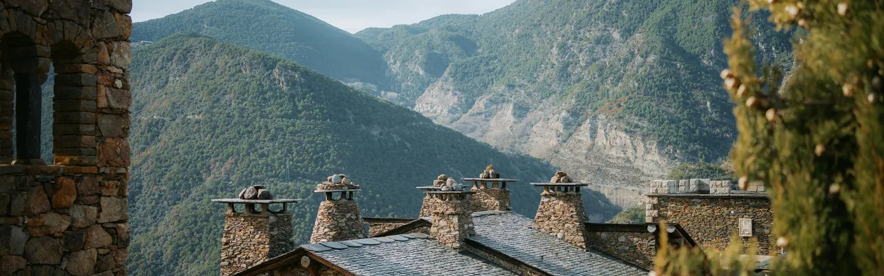 Stone slate rooftops with chimneys against the Pyrenees mountains, Andorra