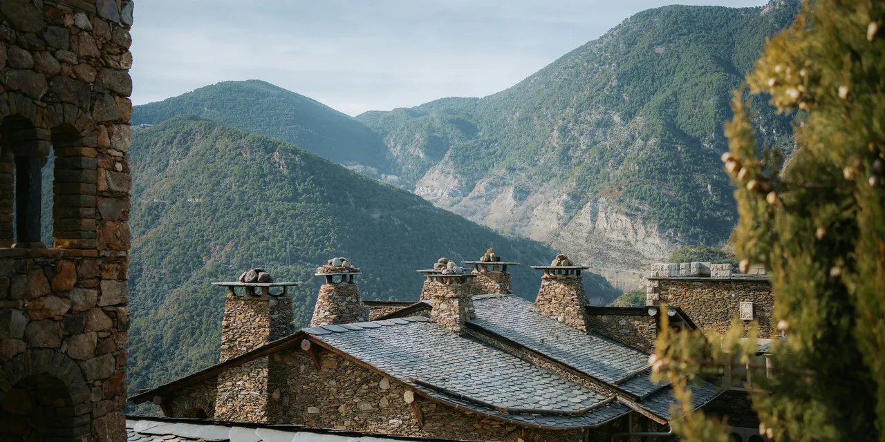 Stone slate rooftops with chimneys against the Pyrenees mountains, Andorra