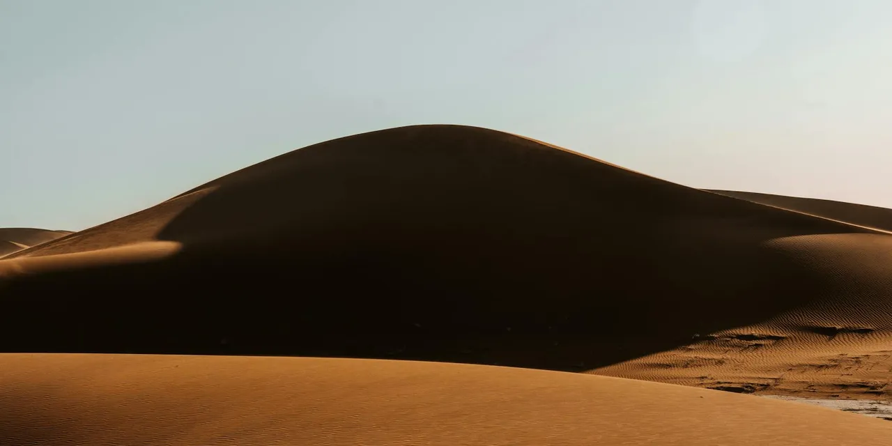 Captivating view of sand dunes in Sahara Desert under a clear sky in Morocco.
