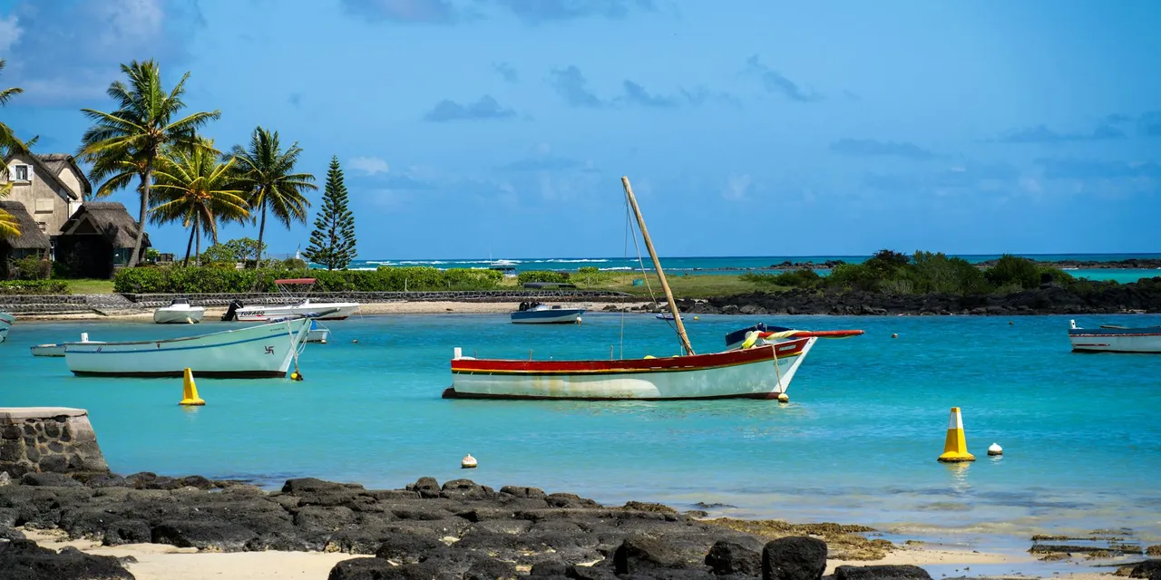 Tranquil beach view with boats, palm trees, and clear blue water in Mauritius.