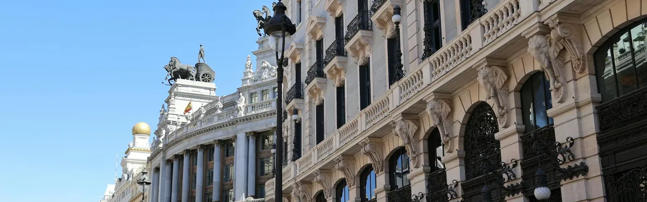 Beautiful architectural buildings in Madrid under a bright blue sky.
