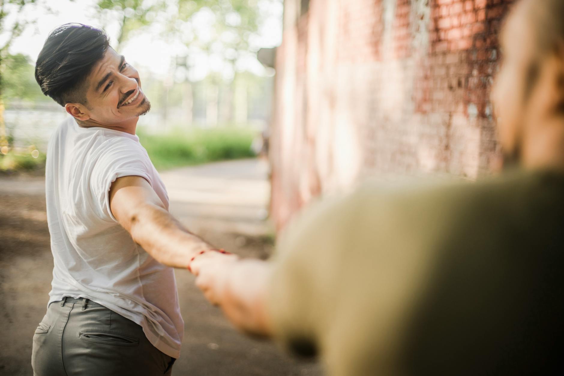 Smiling man leading his partner by the hand along an outdoor path
