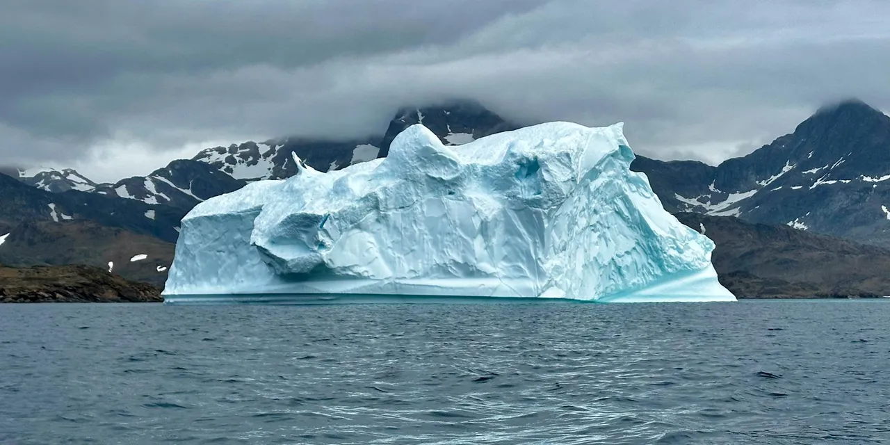 Expansive iceberg floating serenely in the cool waters of Greenland.