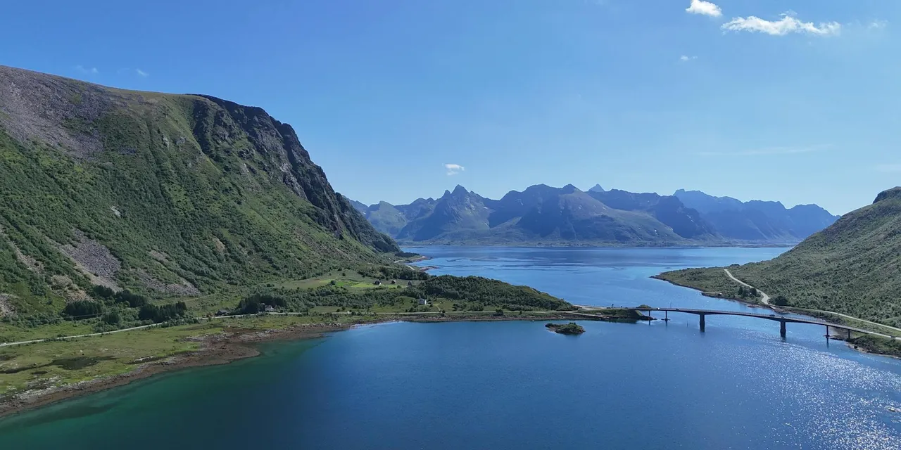 A breathtaking aerial view of the scenic Lofoten Islands in Norway, featuring mountains, water, and a bridge on a clear summer day.