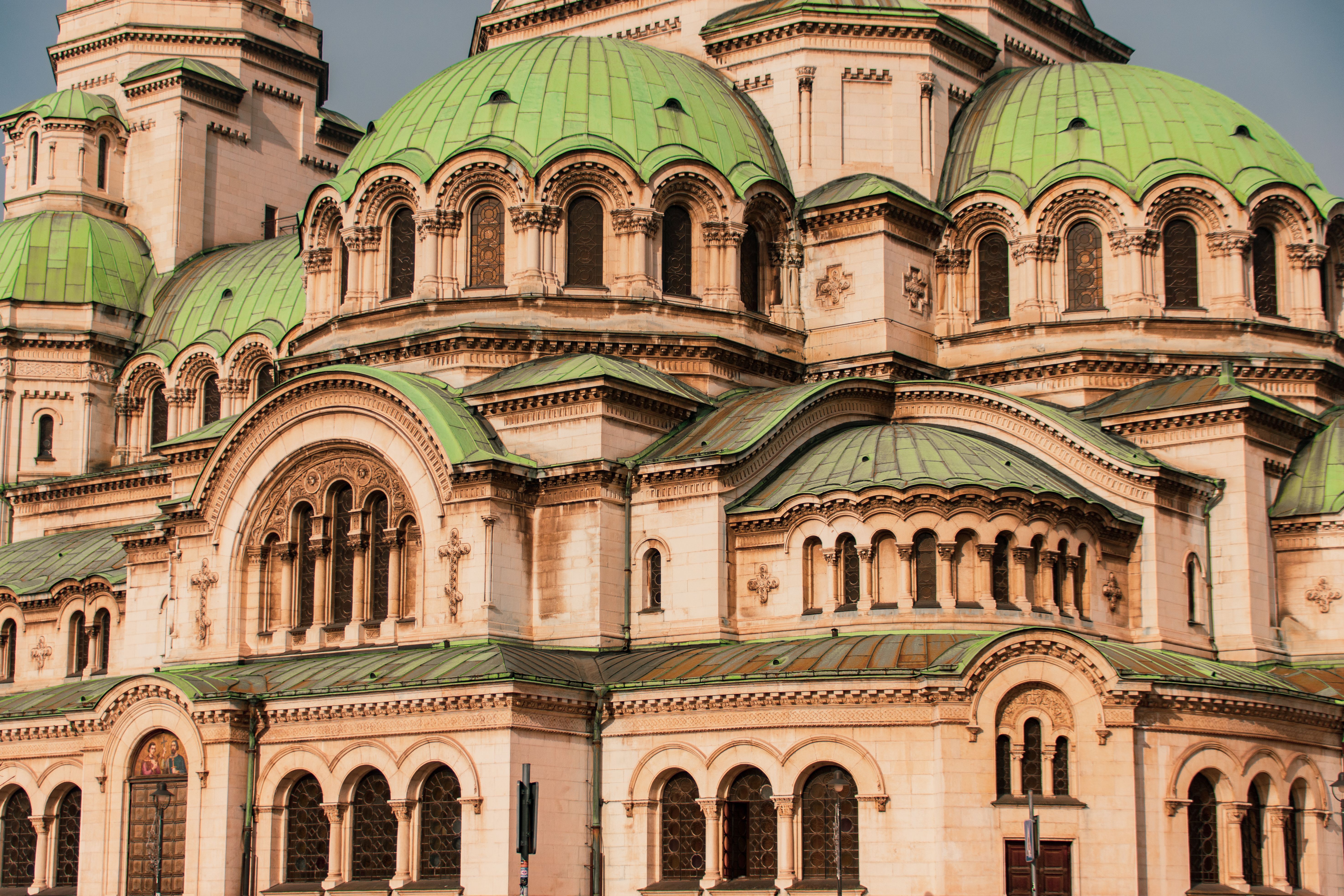 The green copper domes and pale stone facade of a neo-Byzantine cathedral in Sofia.