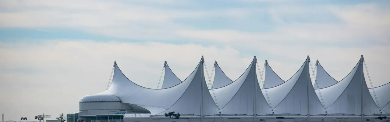 Iconic Canada Place building with its sail-like roof in Vancouver, BC against a blue sky.