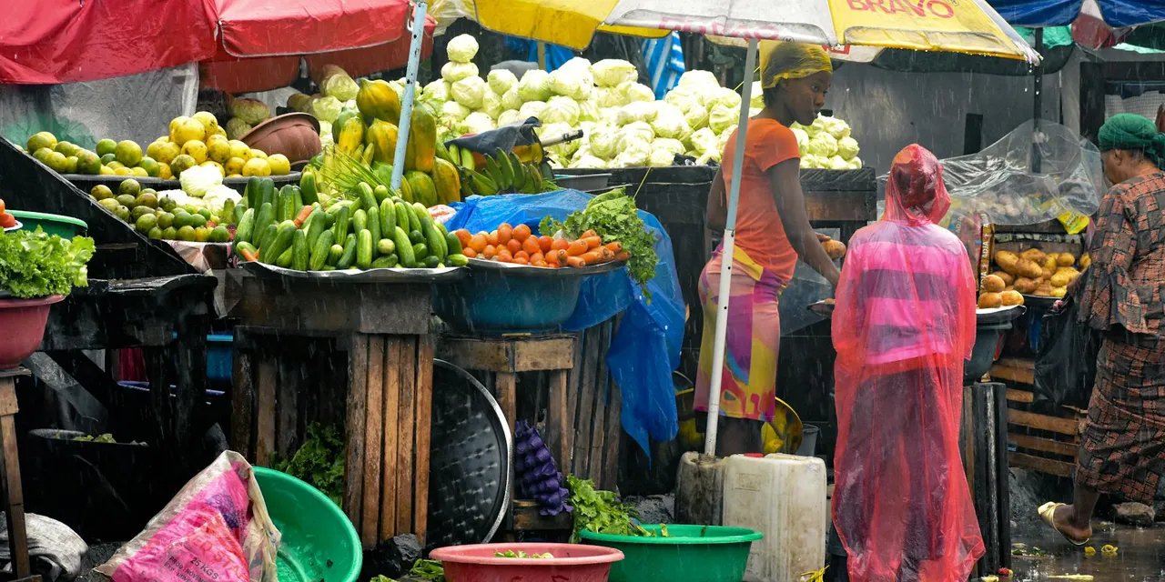 Colorful market with fruits and vegetables in Monrovia, Liberia during rain, showcasing local culture.