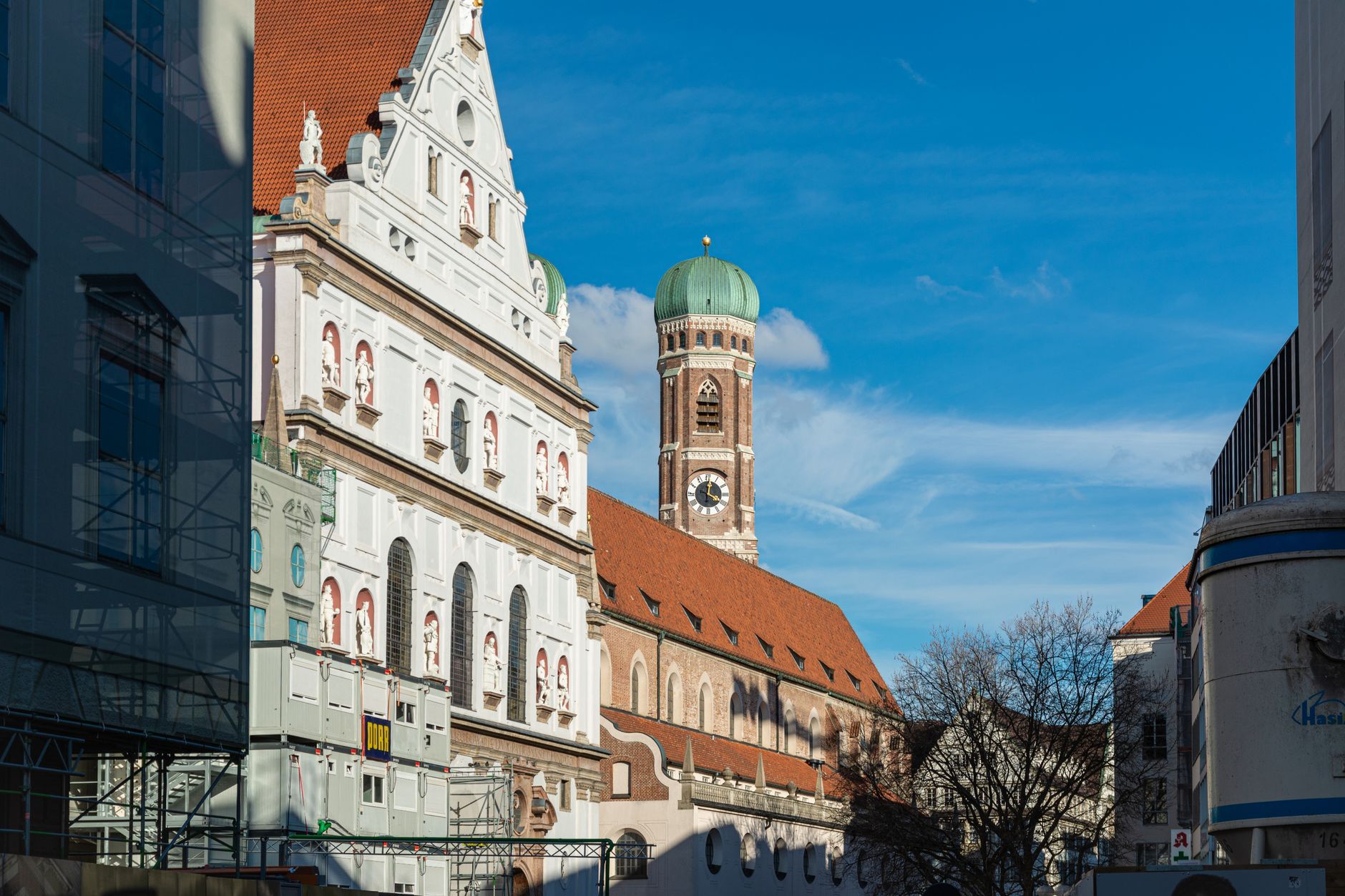 Capture of St. Michael's Church and Frauenkirche tower in Munich, Germany, under a clear blue sky.