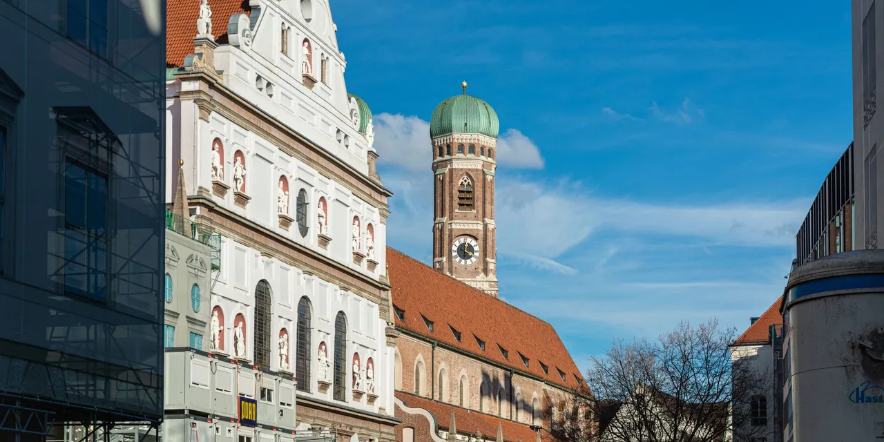 Capture of St. Michael's Church and Frauenkirche tower in Munich, Germany, under a clear blue sky.
