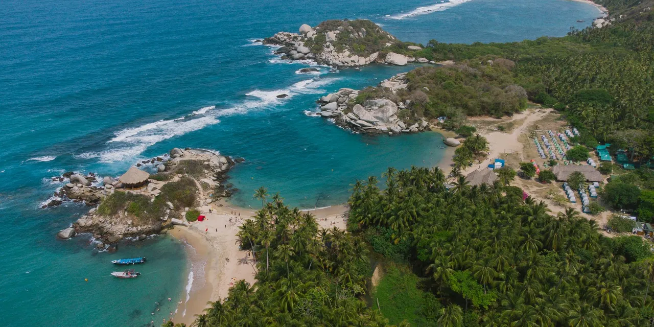 Stunning aerial drone shot of Tayrona National Park's coastline in Colombia, showcasing turquoise waters and lush greenery.