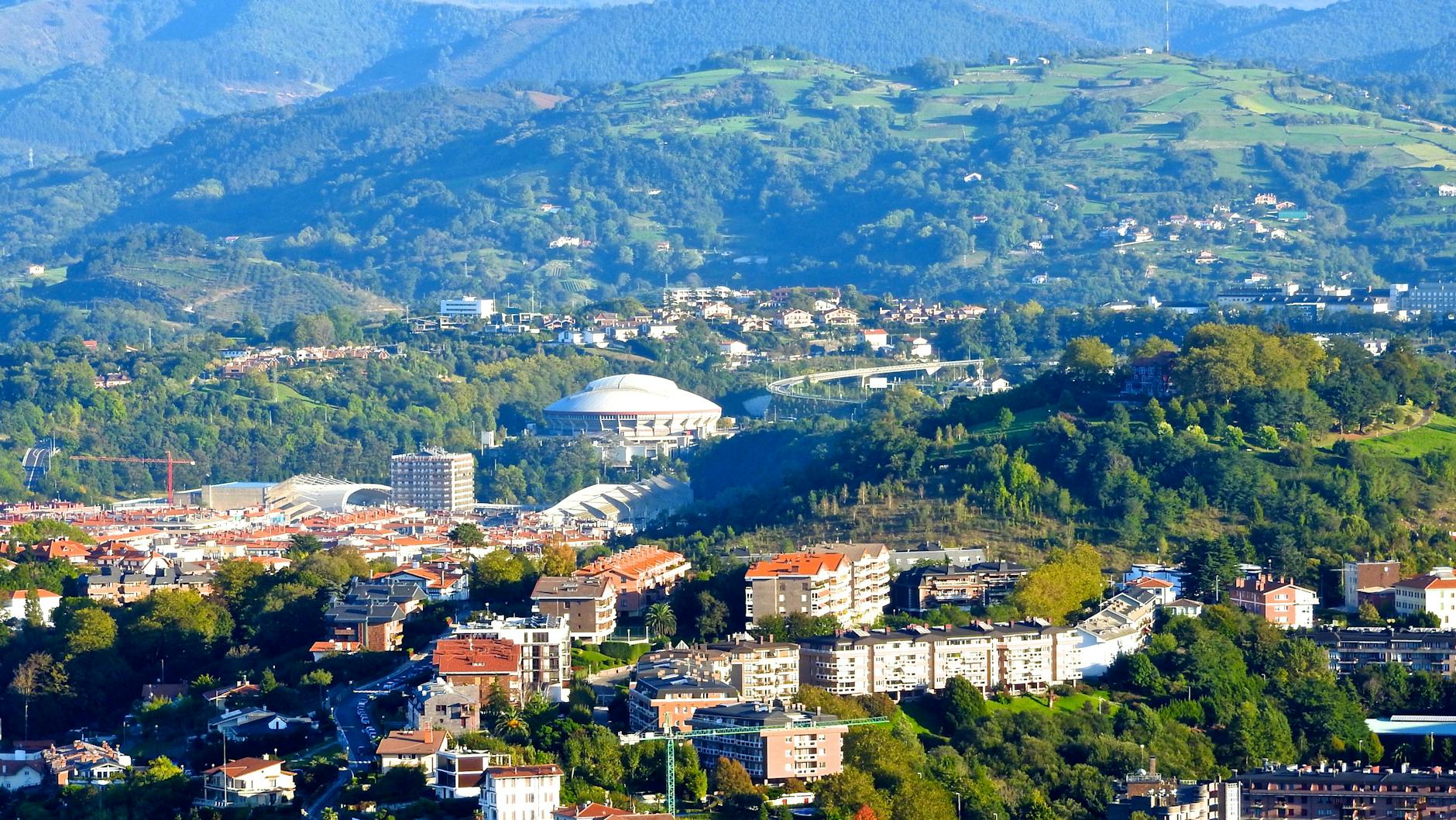 Aerial view of Donostia-San Sebastián with scenic hills and city buildings.