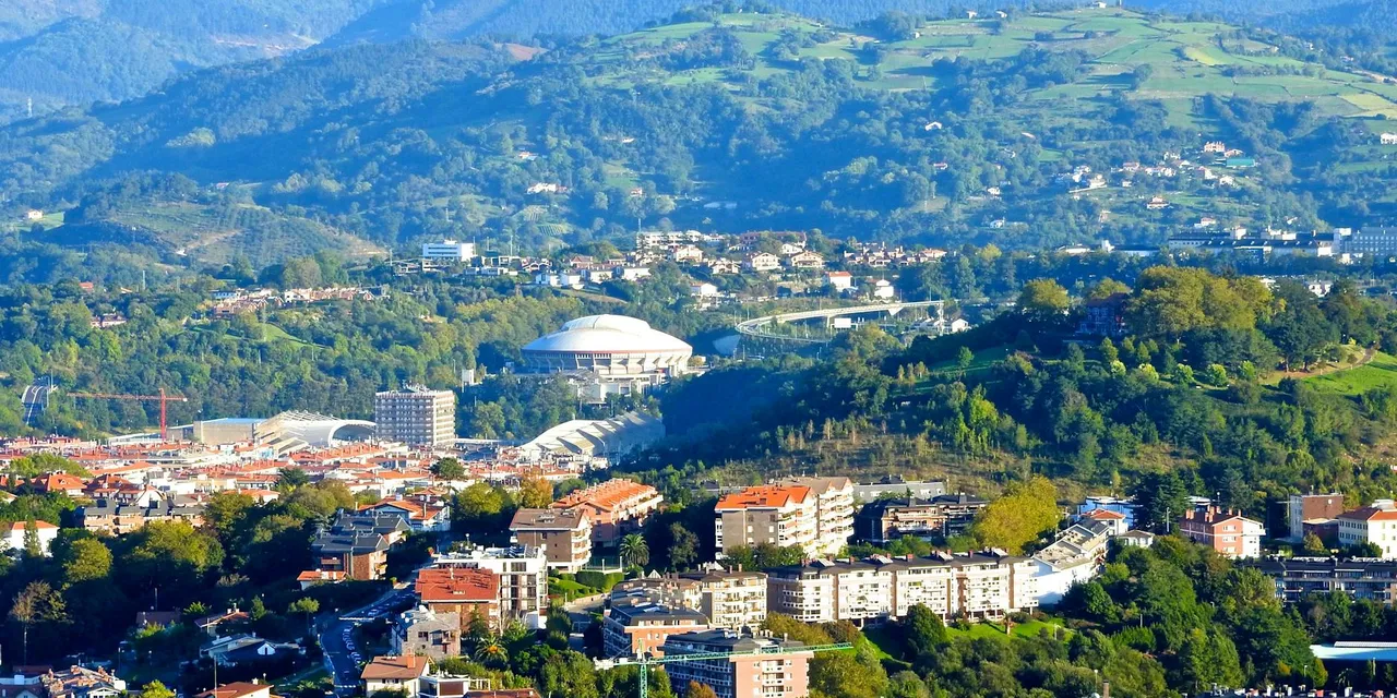 Aerial view of Donostia-San Sebastián with scenic hills and city buildings.