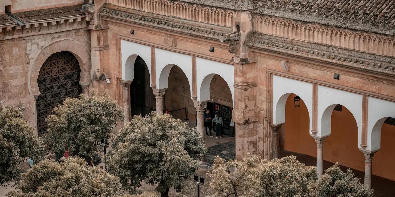 Aerial view of the historic Mosque-Cathedral of Córdoba with its iconic arches and surrounding trees.