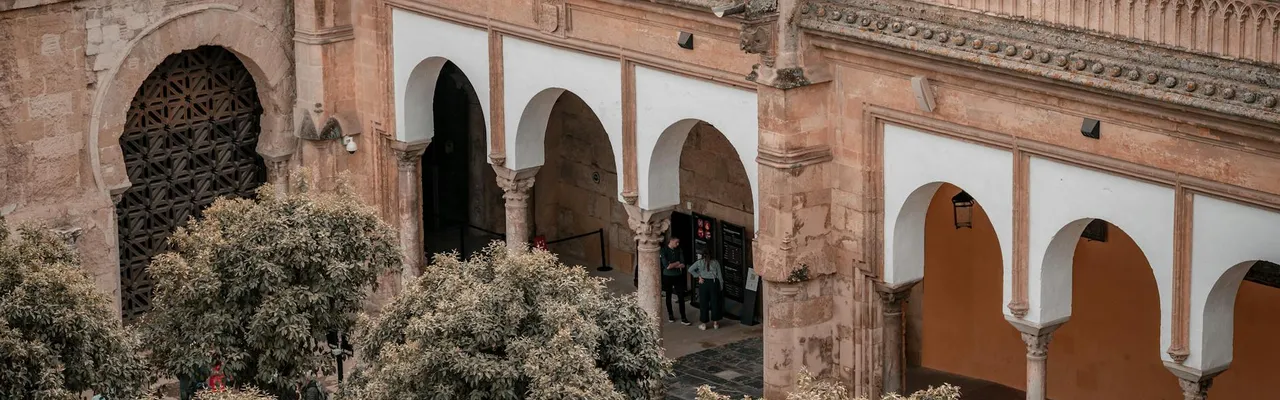Aerial view of the historic Mosque-Cathedral of Córdoba with its iconic arches and surrounding trees.