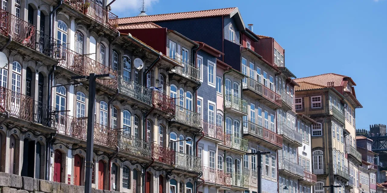 Vibrant, historic waterfront buildings along Porto's scenic riverfront under a clear blue sky.