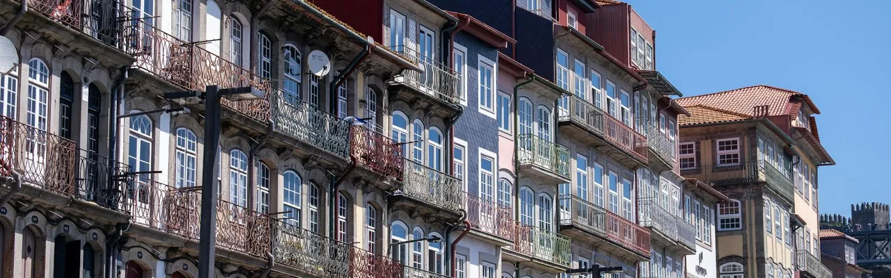 Vibrant, historic waterfront buildings along Porto's scenic riverfront under a clear blue sky.