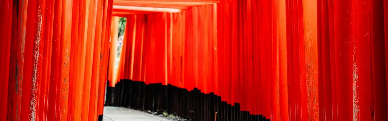 Explore the iconic red torii gates of Fushimi Inari Shrine in Kyoto, Japan, featuring traditional architecture.