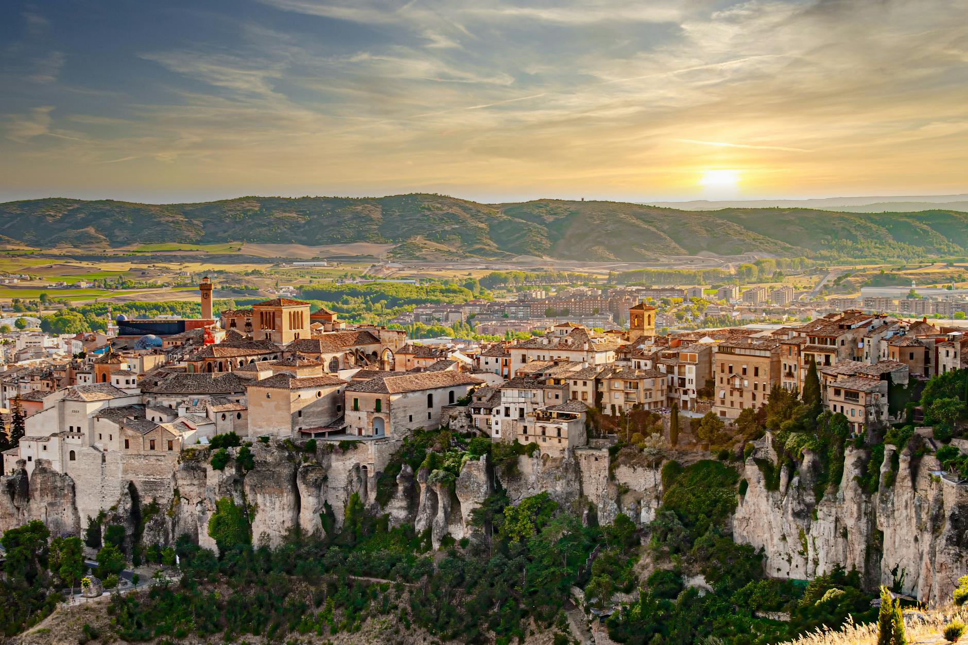 Stunning view of Cuenca, Spain with dramatic cliffs and historic buildings at sunset.