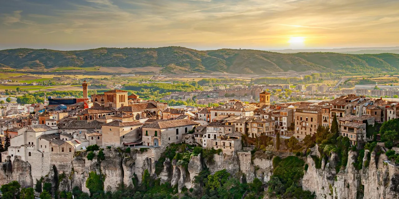Stunning view of Cuenca, Spain with dramatic cliffs and historic buildings at sunset.