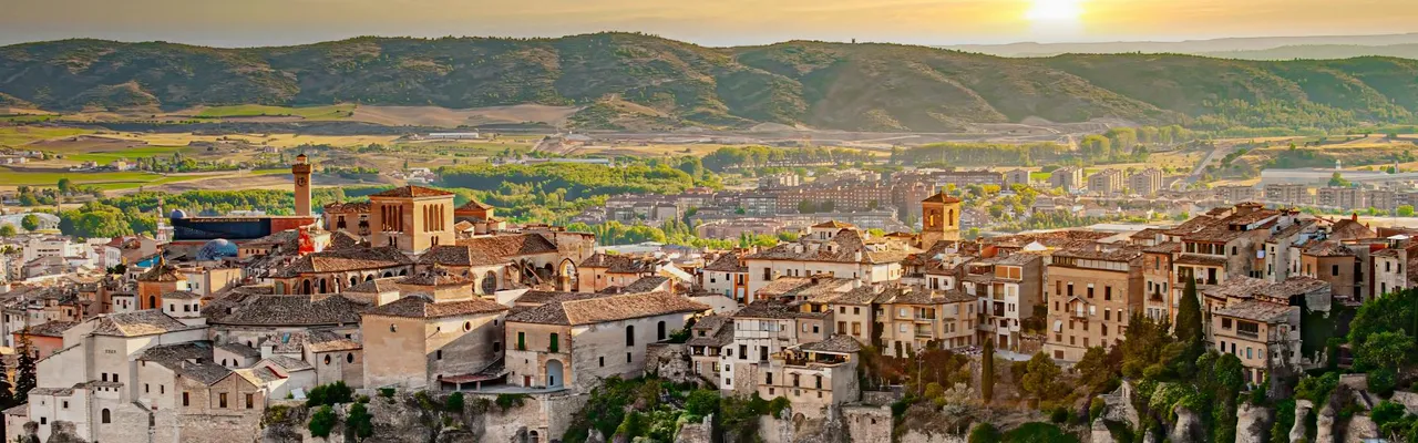 Stunning view of Cuenca, Spain with dramatic cliffs and historic buildings at sunset.