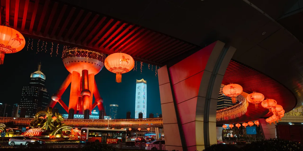 Captivating view of Shanghai's Oriental Pearl Tower at night with red lanterns lighting up the scene.