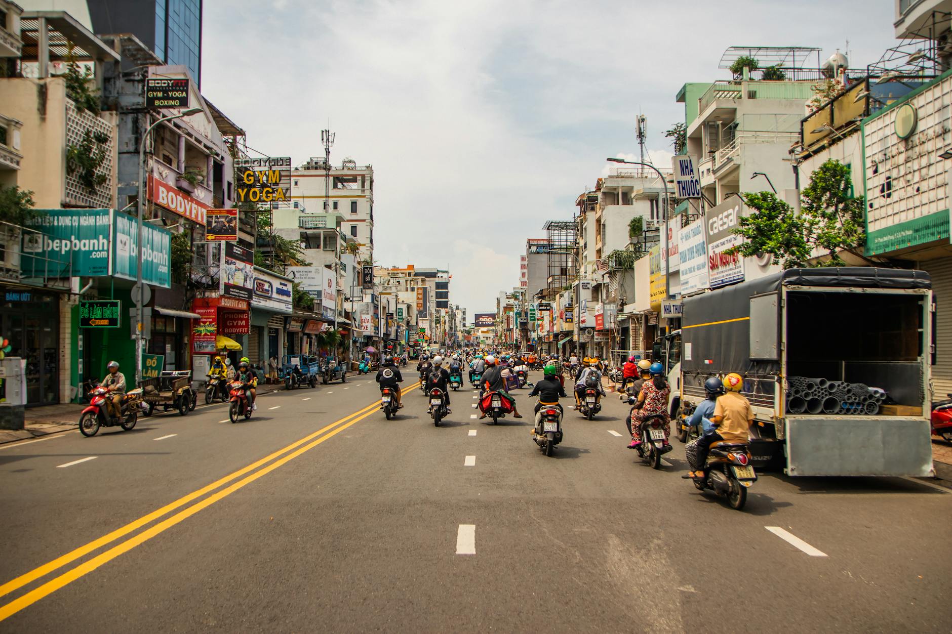 Motorcyclists navigating busy street in vibrant Ho Chi Minh City.