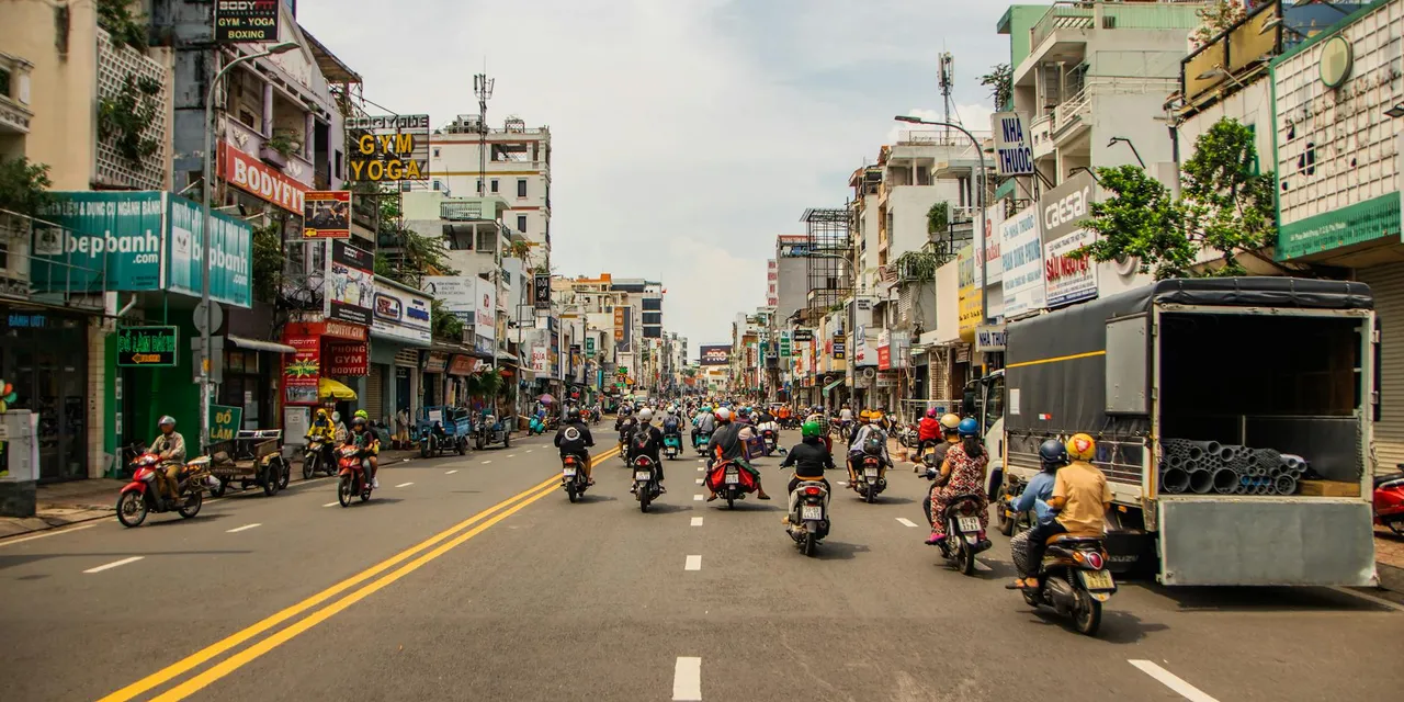 Motorcyclists navigating busy street in vibrant Ho Chi Minh City.