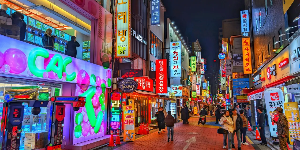 Neon-lit street in Seoul at night with glowing Korean signs and crowds, South Korea