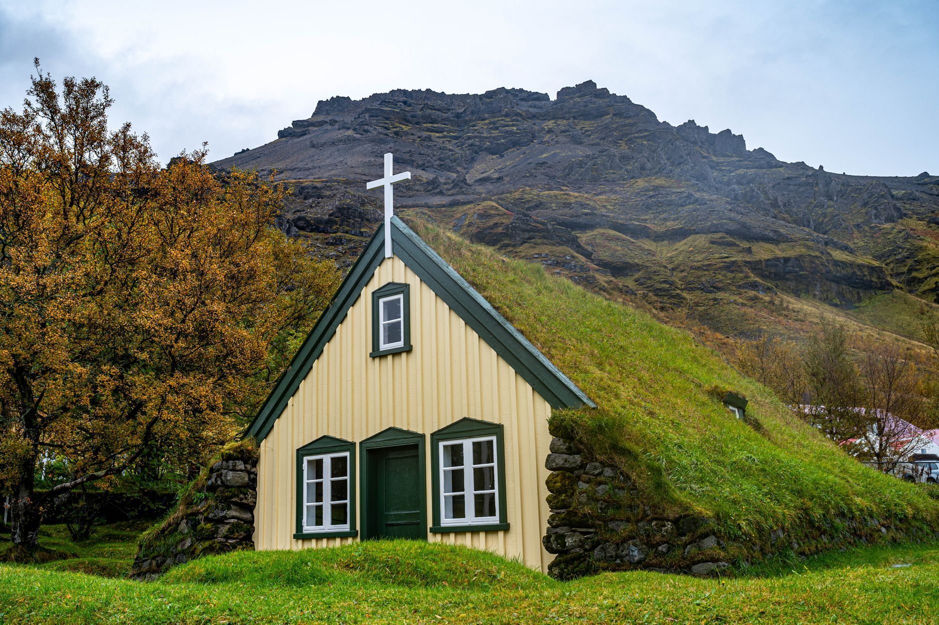 Beautiful Hofskirkja church with distinctive grass roof nestled in scenic Icelandic landscape.