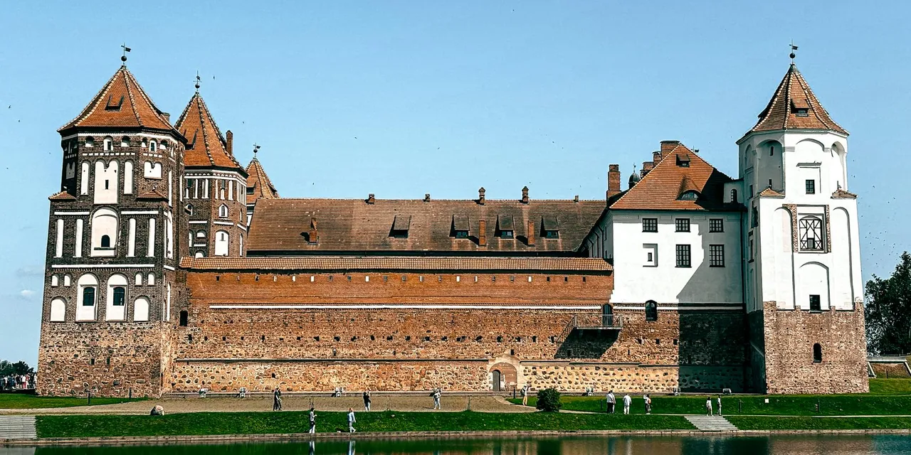 Capture of the historic UNESCO Mir Castle reflecting in the lake, a prime example of Belarusian architecture.