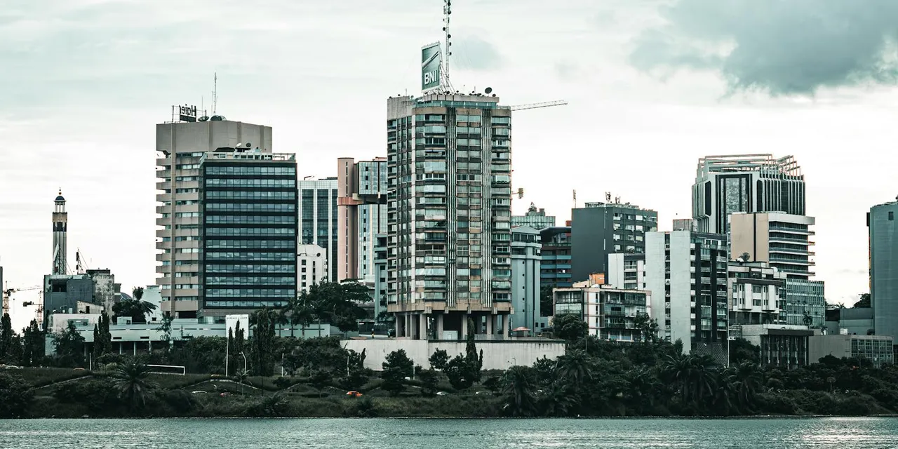 Contemporary cityscape of Abidjan featuring high-rise buildings by the waterfront under overcast skies.