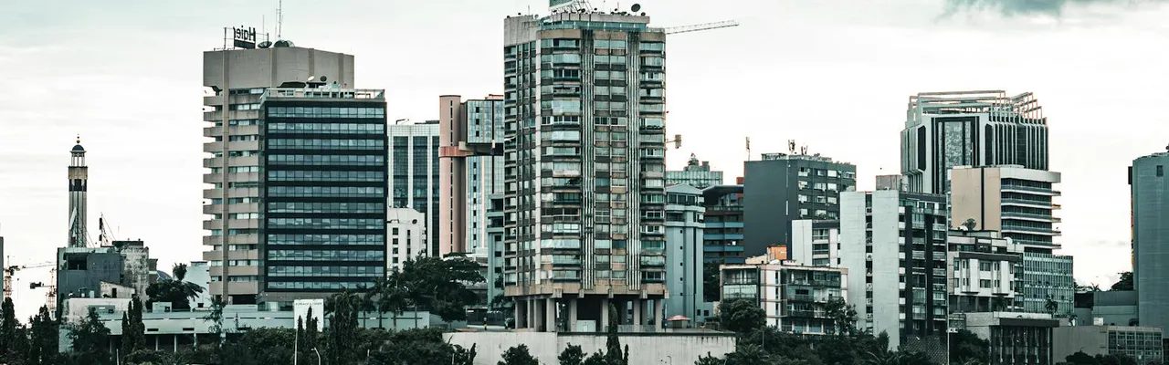 Contemporary cityscape of Abidjan featuring high-rise buildings by the waterfront under overcast skies.