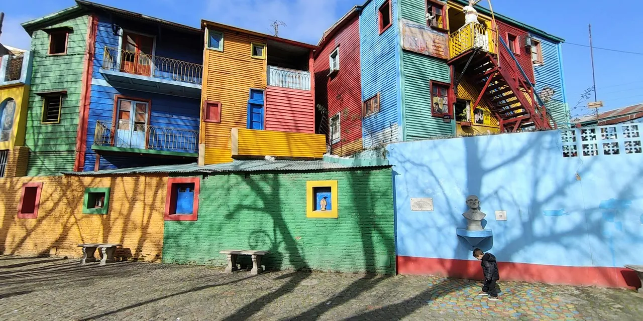 Vividly painted buildings in La Boca, Buenos Aires with shadows and street art.