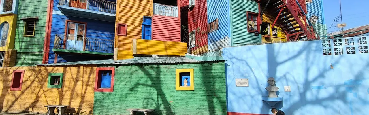 Vividly painted buildings in La Boca, Buenos Aires with shadows and street art.
